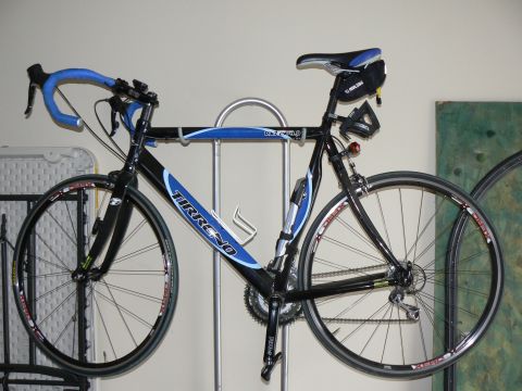 1978 Ford Bronco - A Tirreno road bike is displayed indoors, mounted on a silver rack. It features blue accents on the frame and handlebars.