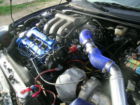 1995 Ford Probe - Customized engine bay a blue valve cover and prominent turbocharger piping.
