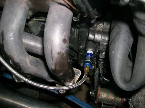 1995 Ford Probe - Detail shot of engine components, including exhaust pipes and a braided oil line with a blue fitting.