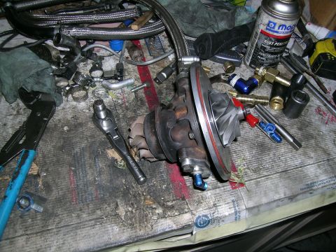 1995 Ford Probe - Turbocharger and various plumbing components laid out on a workbench, suggesting a custom build or repair.