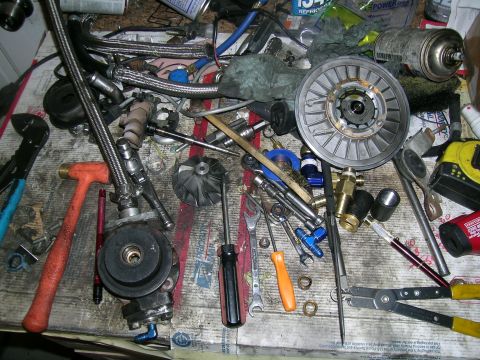 1995 Ford Probe - Various automotive components and tools are spread across a cluttered workbench, suggesting a repair or modification project.