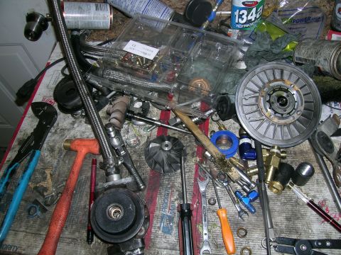 1995 Ford Probe - Various automotive parts and tools are laid out on a cluttered workbench.