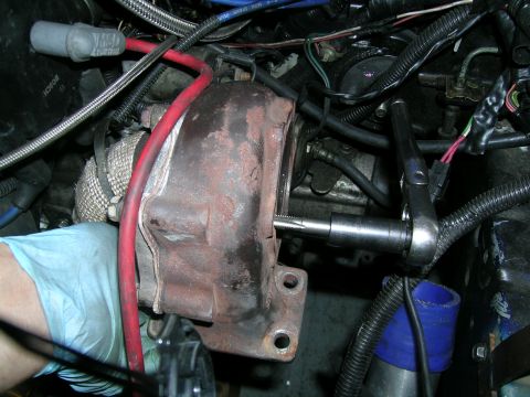 1995 Ford Probe - Mechanic's hand in a blue glove tightens a bolt on a turbocharger with a socket wrench.