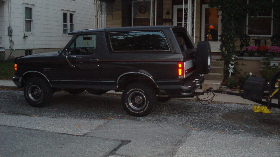 Dark gray SUV, 1987 model year, with a spare tire on the rear door, parked on a street