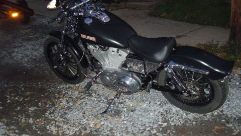 1988 Ford Bronco - A black Harley-Davidson motorcycle is parked on a gravel surface.