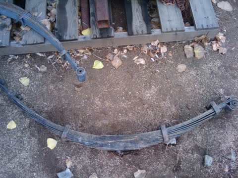 1995 Ford Bronco - Leaf springs are visible in the foreground, resting on the ground next to a wooden pallet.