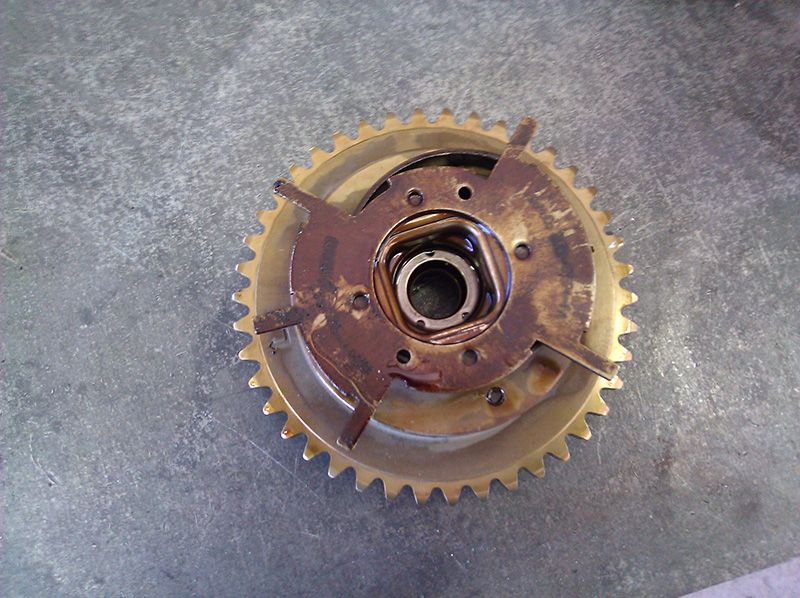 Rusty sprocket and hub assembly with center bearing opening lying on a concrete shop floor