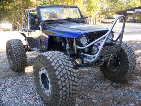 1992 Jeep YJ - A heavily modified Jeep Wrangler sits on a gravel surface, ready for off-road adventures.