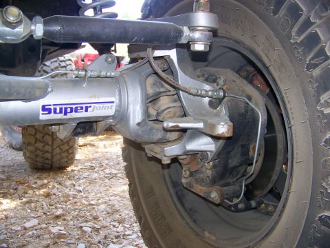 1992 Jeep YJ - This photo shows a close-up of the front axle and suspension components of a Jeep, including the steering linkage and wheel.