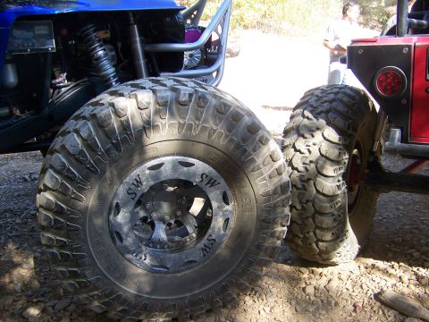 1992 Jeep YJ - Two off-road vehicles are parked side-by-side, their aggressive tire treads and suspension components.