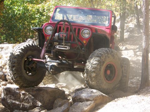 1992 Jeep YJ - This red 1992 Jeep YJ navigates a rocky trail, demonstrating its off-road capabilities.