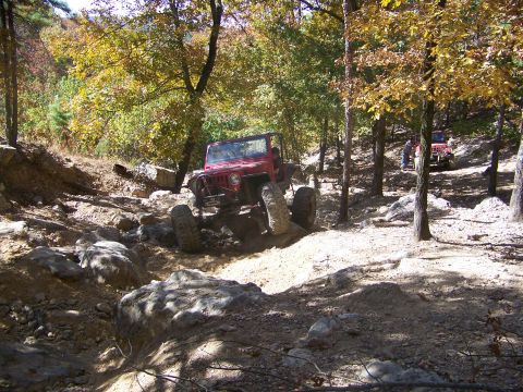 1992 Jeep YJ - Two Jeeps navigate a rocky, wooded trail during an off-road excursion.