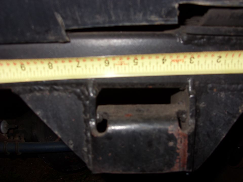 Yellow measuring tape on black metal vehicle frame section
