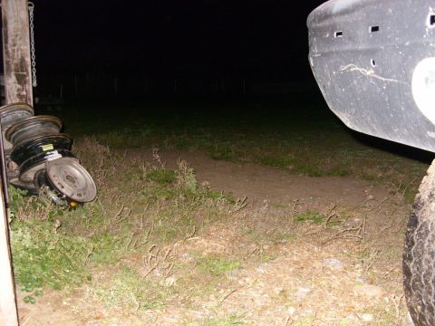 1988 Ford Bronco - A close-up view of a vehicle's bumper and tire, with a stack of tires nearby, taken at night.