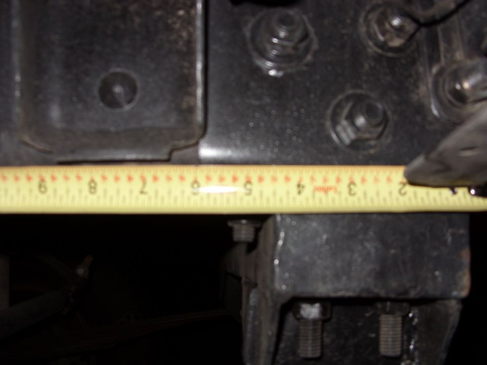 Close-up of black metal vehicle frame with a yellow measuring tape showing approximately 5 inches