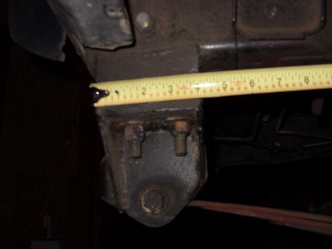 1988 Ford Bronco - A measuring tape is placed against a dark, bolted vehicle frame component.