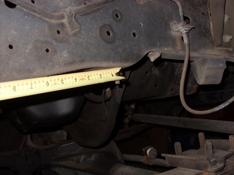 1988 Ford Bronco - Close-up view of vehicle frame and suspension components with a tape measure.