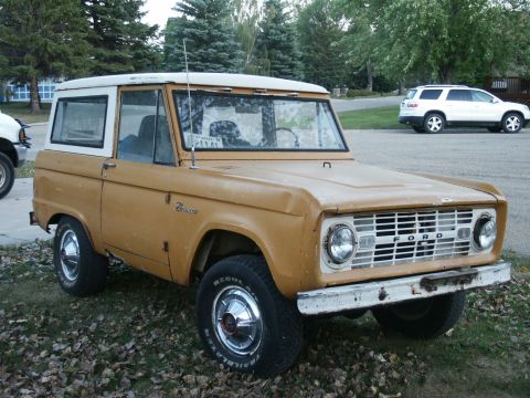 1966 Ford Bronco - A tan Ford Bronco with a white hardtop is parked on a grassy area next to a white SUV.