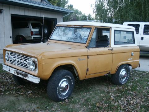 1966 Ford Bronco - A 1966 Ford Bronco is parked outside a garage, with another vehicle visible inside.