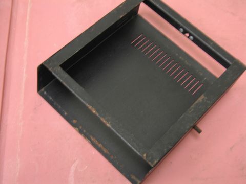 1991 Ford LTD Crown Victoria - A black metal bracket with ventilation slits and some rust is shown against a pink surface.