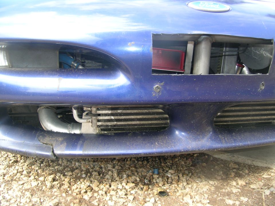 Blue car front bumper removed showing intercooler and turbo piping. Ford logo visible on hood