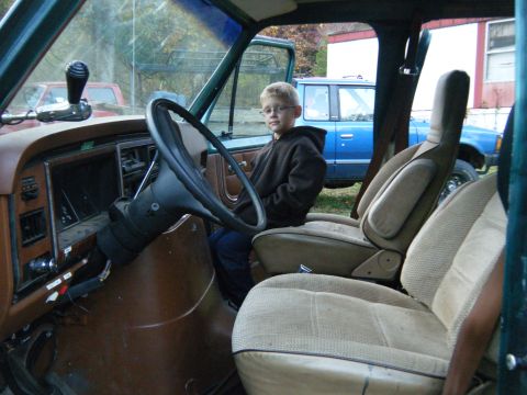 1981 Ford E350 - The interior of a 1981 Ford E350 van is shown, with a young boy seated behind the steering wheel.