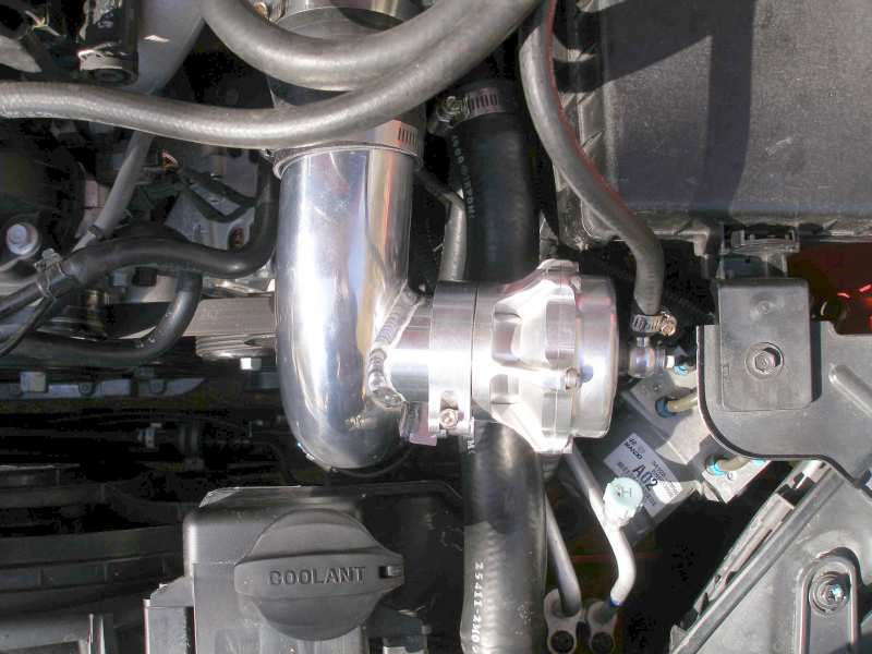 Aftermarket blow-off valve in engine bay with coolant reservoir visible
