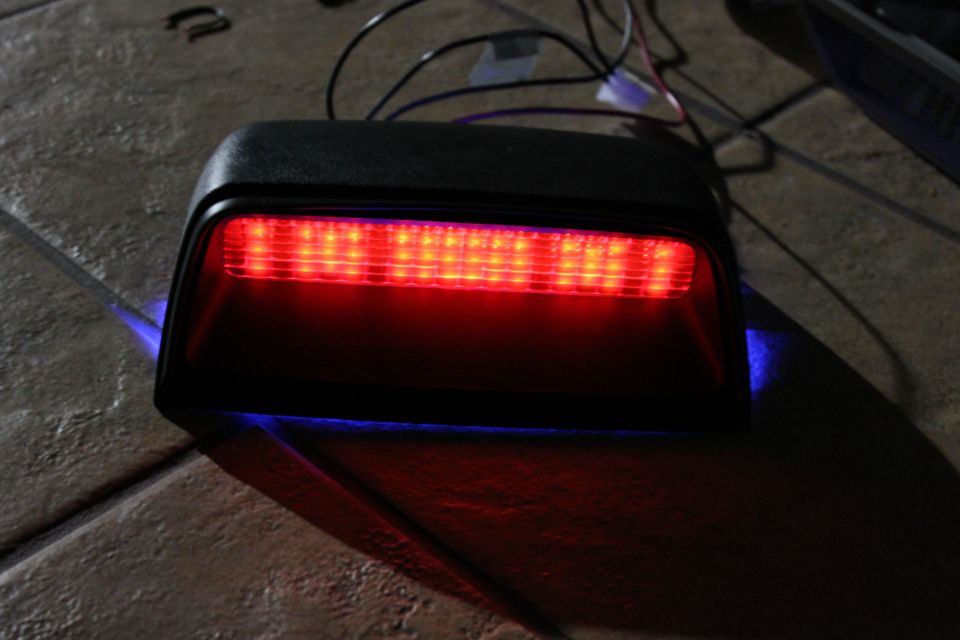 Black LED third brake light lit red on a tile floor with blue underglow during testing