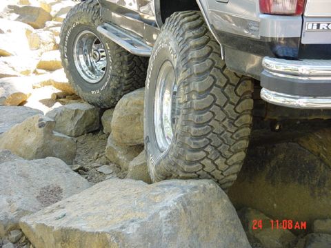 1989 Ford Bronco - A vehicle navigates a rocky terrain, with its large off-road tires gripping the stones.