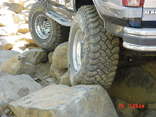 Lifted Ford Bronco on BFGoodrich mud tires crawling over boulders, passenger side low angle