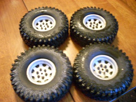 1994 Ford Escort - Four off-road tires with white rims are displayed on a wooden floor.