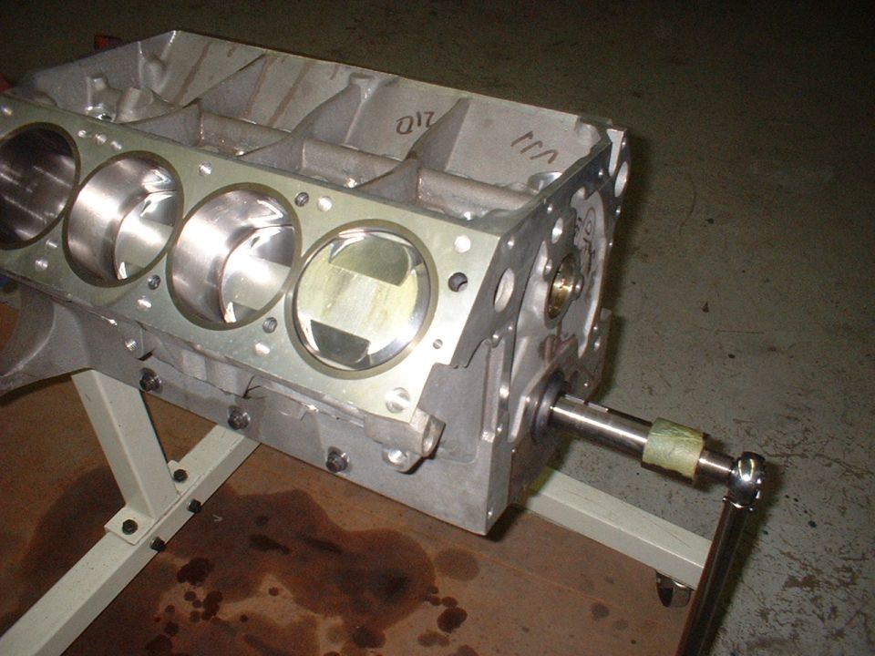 engine block on stand, pistons visible inside cylinders, crankshaft sticking out