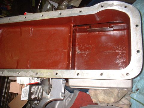 1965 Shelby Cobra - Close-up view of a red-painted oil pan, likely a replacement part, with a silver gasket flange visible.
