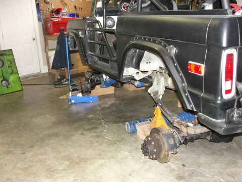 1967 Ford Mustang - A black Ford Bronco is undergoing modifications in a garage, with its suspension and axles removed.