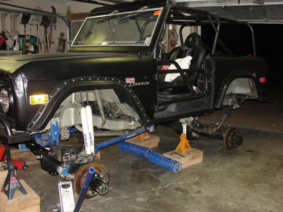 Black Ford Bronco with roll cage, undergoing suspension work