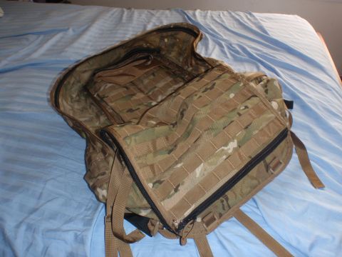 1991 Ford Bronco - A multi-camouflaged backpack is open on a bed, revealing its interior compartments and straps.