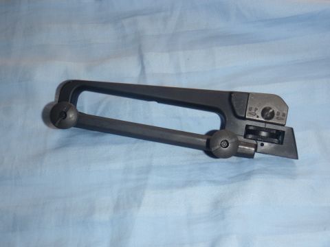 1991 Ford Bronco - A close-up view of a carrying handle with an adjustable rear sight mechanism is shown against a blue striped background.