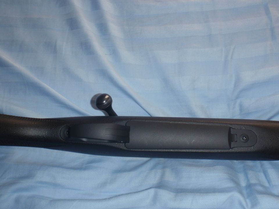 Bolt action rifle receiver with bolt handle visible, resting on a blue cloth