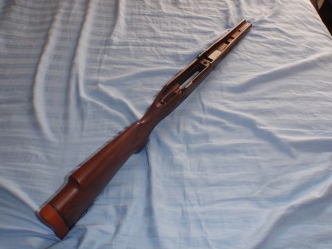 1991 Ford Bronco - A wooden gun stock is shown from an elevated angle against a blue fabric background.