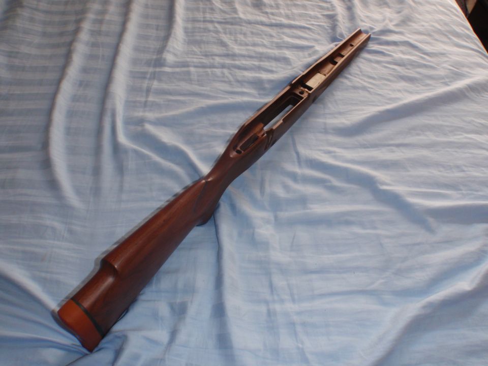 Wooden gun stock with orange butt pad, lying on a blue cloth