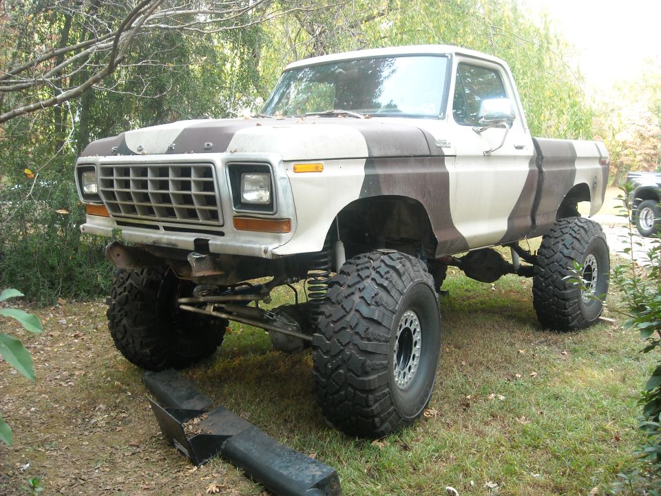 Lifted 1977 Ford F-150 pickup truck with camouflage paint, large off-road tires, and custom suspension