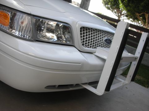2004 Ford Crown Victoria - Front close-up of a white Ford Crown Victoria with the honeycomb grille and Ford oval, fitted with a white-painted police-style push bar wi…