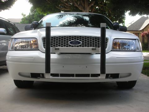 2004 Ford Crown Victoria - Front of a white Ford Crown Victoria sedan fitted with two vertical black push-bar uprights at the bumper.