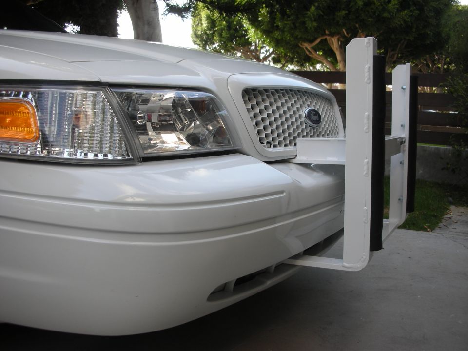 White Ford sedan front corner with clear headlight and mounted white push bumper upright
