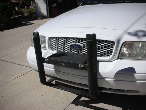 2004 Ford Crown Victoria - Front three-quarter view of a white Ford Crown Victoria on a sunny driveway with a black push bumper test-fitted to the front bumper, its t…