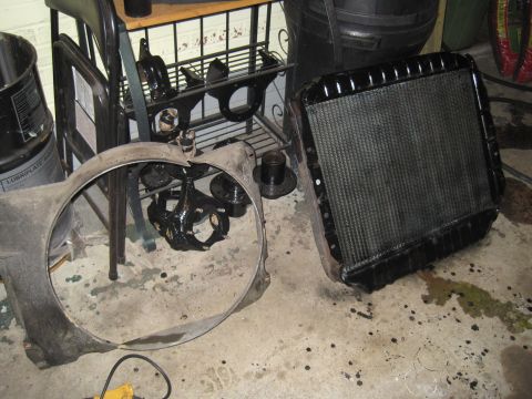 1979 Ford Bronco - Engine parts, including a radiator and fan shroud, are laid out on a concrete floor.
