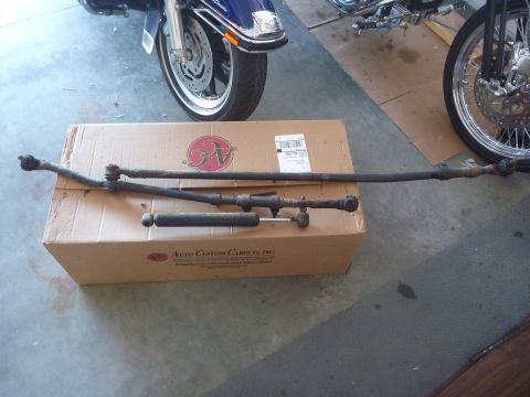 1997 Dodge 2500 - A steering linkage and shock absorber are laid out on a cardboard box, with parts of two motorcycles in the background.