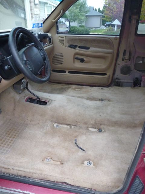 1997 Dodge 2500 - The interior of a Dodge truck shows the floor with the carpet removed, revealing mounting points and wiring.