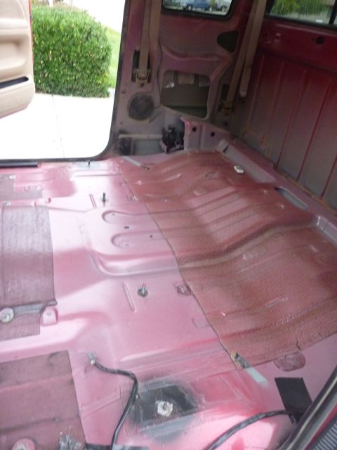 1997 Dodge 2500 - The interior of a red 1997 Dodge 2500 pickup truck, showing the floor with the carpet removed and exposed metal.