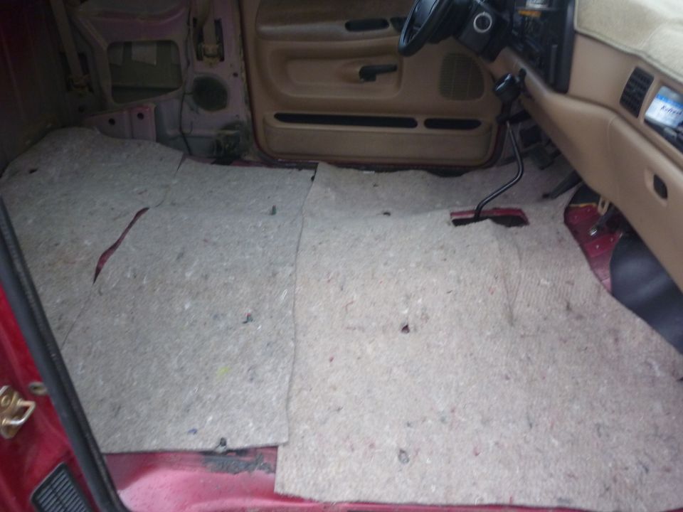Interior of a red truck, showing the floor with carpet removed and exposed metal